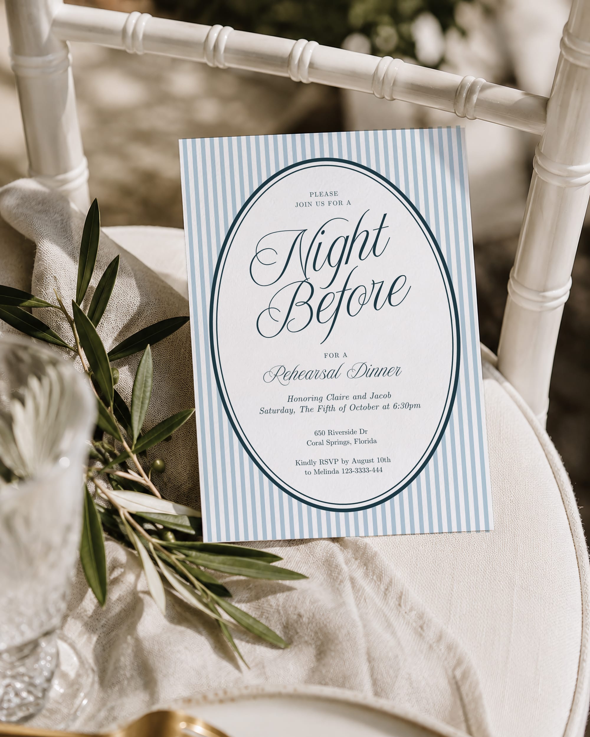 Blue striped Night Before invitation displayed against a white chair